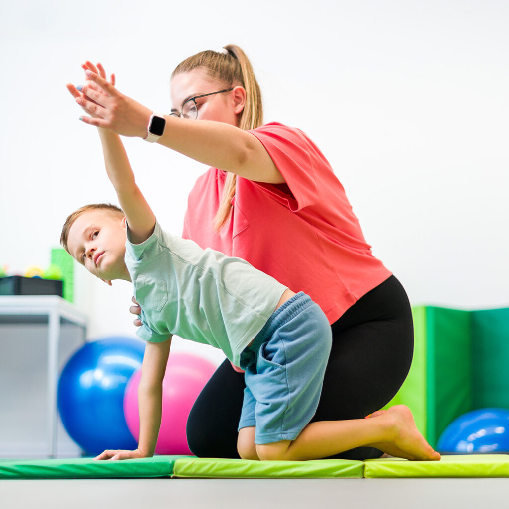 Physical Therapist working with young boy wearing shorts and tshirt