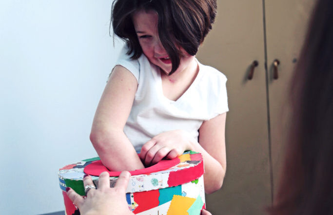 Small girl with box reaching hand in