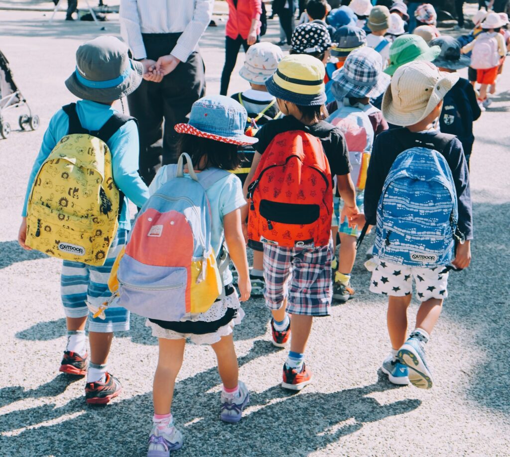 Children wearing bucket hats and backpacks walking outside