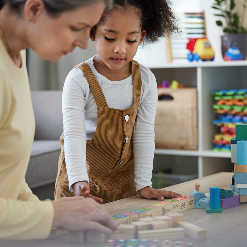 Child wearing velvet overalls working with blocks in classroom
