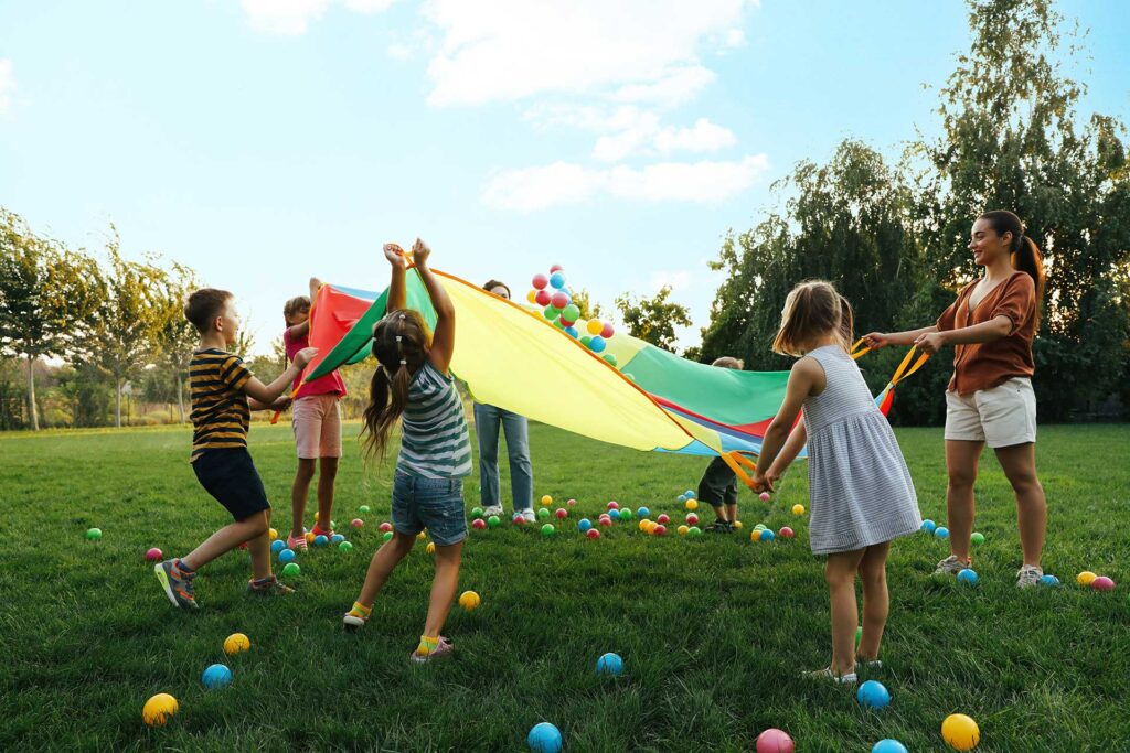 Children playing outside with parachute and balls