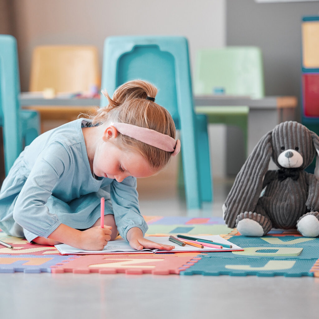 Little girl wearing blue dress drawing with colored pencils