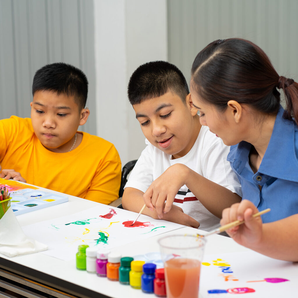 Autistic students painting with teacher