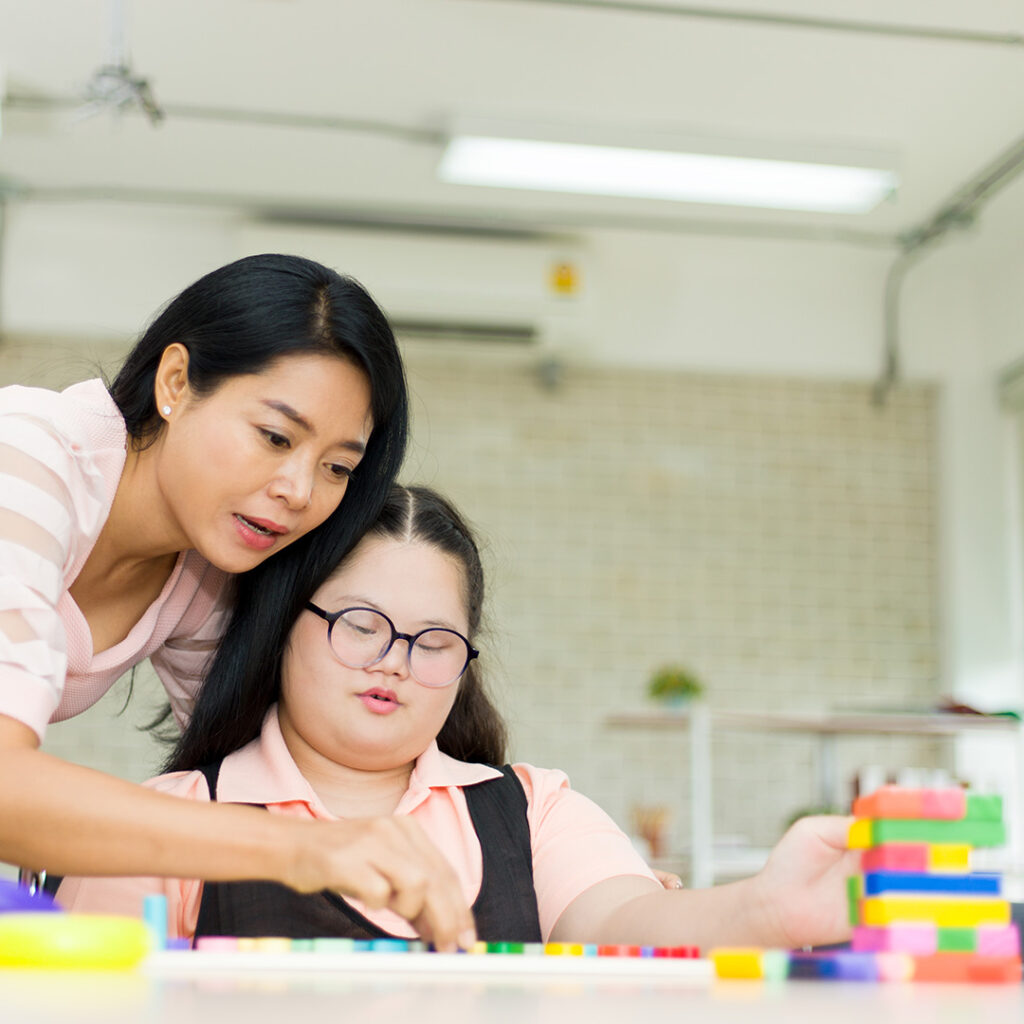 Autistic girl working with teacher in classroom